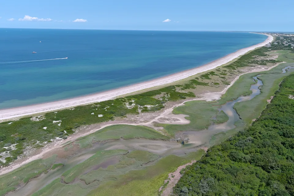 Long pale barrier beach dividing the ocean from a Cape Cod marsh